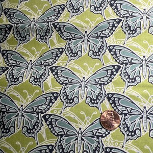 以下が含まれることがあります： 緑色の生地に、黒と青の蝶が繰り返しパターンで描かれています。蝶は様式化されており、詳細なデザインが施されています。
