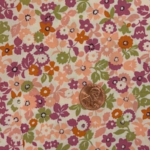 May include: A fabric featuring a dense floral pattern with small blossoms in shades of purple, peach, orange, and light green on an off-white background. A copper-colored U.S. penny is placed on the fabric to provide a sense of scale.