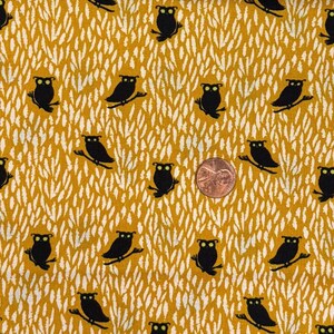 Puede incluir: Tela de color amarillo mostaza con un patrón repetido de búhos negros posados en ramas y formas blancas en forma de hojas. Se incluye una moneda para la escala. La tela es probablemente de algodón, adecuada para proyectos de acolchado o artesanía.