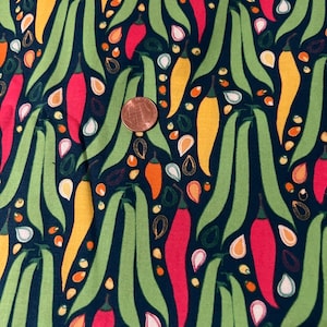 May include: A dark blue fabric with a repeating pattern of green beans, red chili peppers, and yellow peppers. The fabric is decorated with small white and orange seeds.