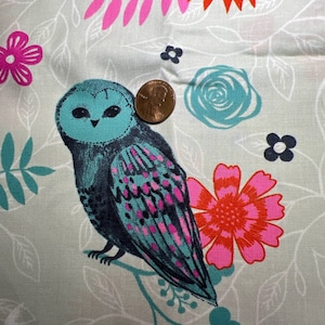 Puede incluir: Un búho azul verdoso con detalles rosas y negros posado en una rama con hojas azul verdosas. El búho está rodeado de flores rosas, rojas y azul verdosas sobre un fondo gris claro.