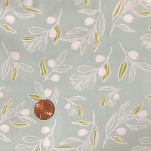 Puede incluir: Tela azul claro con un patrón repetido de ramas de olivo. El diseño presenta contornos blancos de hojas y aceitunas, con acentos verdes. Se incluye una moneda para la escala.