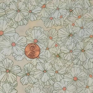 May include: A fabric with a repeating pattern of white daisy-like flowers with orange centers and green stems. The flowers are set against a light beige background. A penny is included for scale.