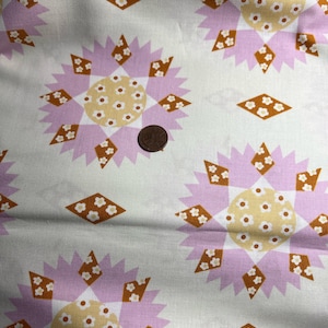 May include: White fabric with a repeating pattern of pink and brown starburst shapes with white flower accents. The fabric has a subtle texture.