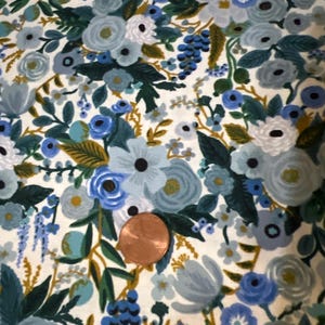 Puede incluir: Una tela blanca con un patr&oacute;n floral azul y verde. La tela presenta una variedad de flores, hojas y enredaderas. Las flores son en tonos de azul, verde y blanco. Las hojas son en tonos de verde y dorado. Las enredaderas son en tonos de verde y marr&oacute;n.