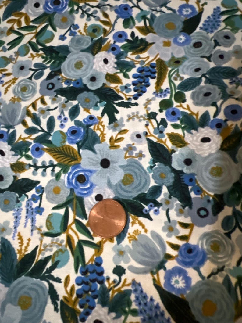 Puede incluir: Una tela blanca con un patr&oacute;n floral azul y verde. La tela presenta una variedad de flores, hojas y enredaderas. Las flores son en tonos de azul, verde y blanco. Las hojas son en tonos de verde y dorado. Las enredaderas son en tonos de verde y marr&oacute;n.