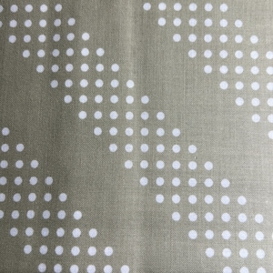 May include: A close-up of a beige fabric with a white polka dot pattern. The dots are arranged in a repeating pattern of curved lines.