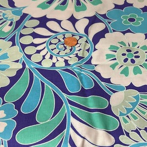 May include: A close-up of a fabric with a floral pattern. The design features large white flowers with teal and green accents, set against a deep purple background. Teal and light blue leaves and swirls complete the design.