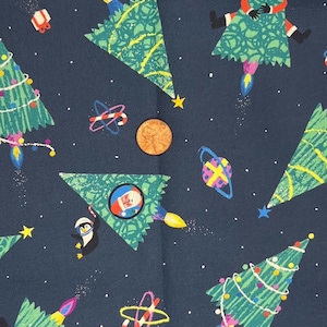 May include: Dark blue fabric with a repeating pattern of Christmas trees, Santa Claus, penguins, and candy canes. The trees are decorated with lights and stars. The design includes a penny for scale.