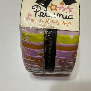 May include: A stack of fabric strips wrapped in clear plastic, labelled Petunia by Kimberly Kight and Star Society. The fabric features horizontal bands in shades of lavender, lime green, and orange, with floral patterns and white polka dots.