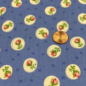May include: Blue fabric with a white and green floral pattern. The fabric is covered in small white circles with a green stem and red rose inside each circle.