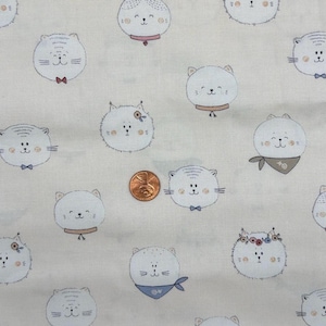 May include: Cream-coloured fabric featuring a repeating pattern of cartoon cat faces. Each cat has a round face and is wearing a bow tie, bandana, or flower crown. A penny is included for scale.