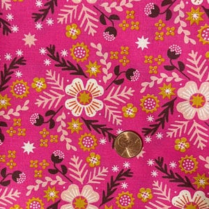 May include: A vibrant pink fabric featuring a repeating pattern of stylized flowers, leaves, and star shapes in shades of cream, mustard yellow, and dark brown. A copper-colored U.S. penny is placed on the fabric for scale, measuring 0.75 inches.