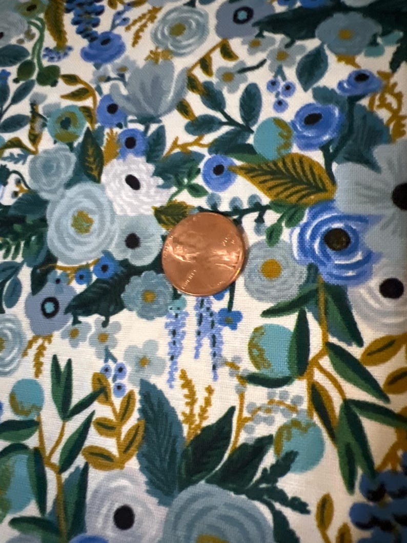 Puede incluir: Una tela blanca con un patr&oacute;n floral azul y verde. La tela presenta una variedad de flores, hojas y bayas. Las flores son en tonos de azul, verde y blanco. Las hojas son en tonos de verde y dorado. Las bayas son en tonos de azul y verde.