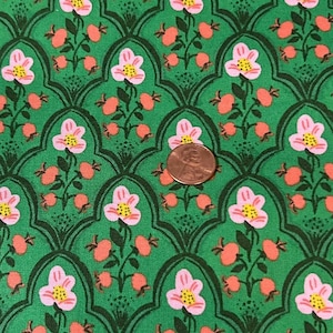 Puede incluir: Primer plano de una tela verde con un patrón floral repetitivo. El diseño presenta flores rosas y amarillas, y bayas naranjas, sobre un fondo verde oscuro. Se incluye una moneda para la escala.