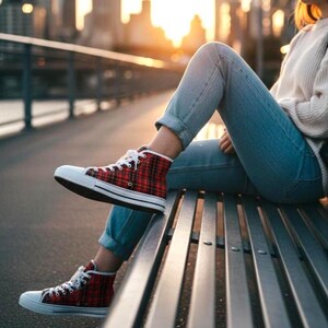 Pu&ograve; includere: Sneakers alte con tomaia in tessuto a quadri rosso e nero, lacci bianchi e punta e suola in gomma bianca. Le scarpe sono indossate con jeans azzurri e un maglione in maglia color crema, che mostrano uno stile di calzature casual classico.