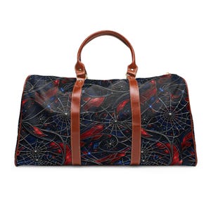 Könnte beinhalten: Eine Reisetasche mit einem dunklen Muster aus roten und blauen geometrischen Formen, durchzogen von weißen Spinnennetzen und kleinen Spinnenabbildungen. Die Tasche hat zwei braune Griffe in Lederoptik und passende vertikale Zierstreifen.