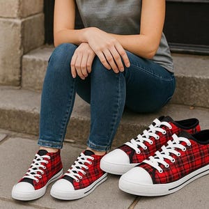 Pu&ograve; includere: Un paio di sneakers in tela a quadri rossi e neri con punta in gomma bianca, lacci bianchi e suole bianche con una sottile striscia nera. Le scarpe presentano un design basso con finiture nere attorno al colletto e agli occhielli.