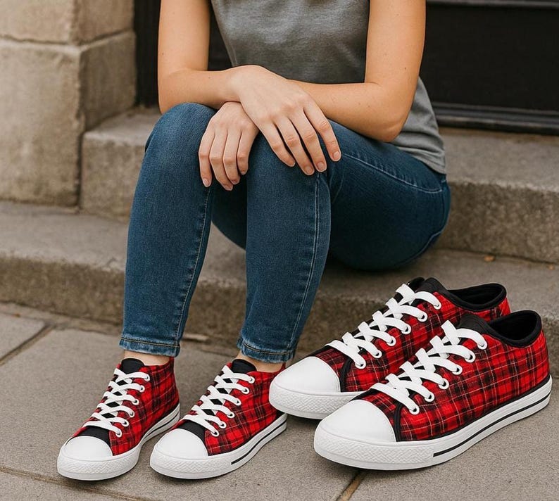 Pu&ograve; includere: Un paio di sneakers in tela a quadri rossi e neri con punta in gomma bianca, lacci bianchi e suole bianche con una sottile striscia nera. Le scarpe presentano un design basso con finiture nere attorno al colletto e agli occhielli.