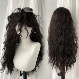 Puede incluir: Una peluca ondulada de color marrón oscuro exhibida en una cabeza de maniquí, con unas gafas de sol plateadas encima. La peluca tiene mechones largos y fluidos y una línea de cabello de aspecto natural. Una segunda vista muestra la parte posterior del cabello.