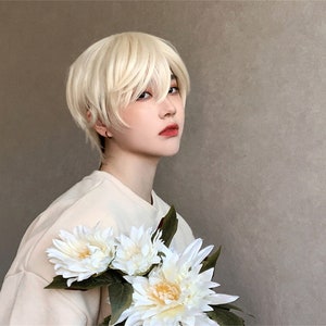 May include: A person wearing a short, layered, blonde wig. The person is holding a bouquet of white flowers with green leaves. The person is wearing a light-colored shirt. The background is a solid, neutral color.