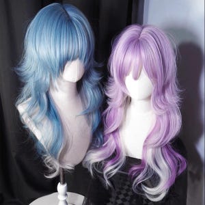May include: Two wigs on mannequin heads. One wig is light blue with darker blue lowlights, and the other is purple with white and purple lowlights. Both wigs have long, wavy layers and bangs.