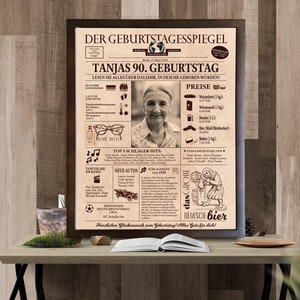 May include: A vintage-style newspaper-themed poster celebrating a 90th birthday. The poster features a photo of a woman, a list of prices for common goods in 1939, and a section highlighting popular music and movies from that year. The poster is framed in a brown wood frame.