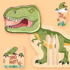 Könnte beinhalten: Ein dinosaurierförmiger Pappteller mit einem grünen T-Rex, ein passender Pappbecher mit T-Rex-Grafik und dem Text DINO PARTY, eine quadratische Serviette mit gleichem Text und Motiv sowie ein Holzlöffel, eine Gabel und ein Messer.