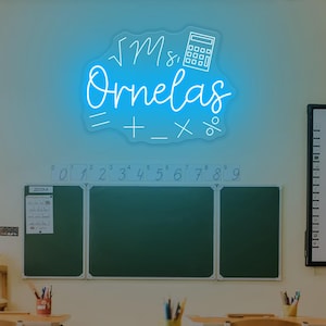May include: A neon sign in a classroom setting. The sign, in bright blue, displays the name "Ornelas" with mathematical symbols and a calculator icon. Desks and chairs are in the foreground, with a chalkboard and whiteboard in the background.