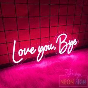May include: A neon sign with the words "Love you, Bye" in a white script font. The sign is mounted on a clear acrylic backing and emits a bright pink glow. The background is a red tiled wall.