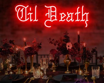 May include: A neon sign in red script reads "Til Death" above a table setting. The table is set with dark plates, gold-toned vases, and floral arrangements. Candles and glassware complete the gothic-themed decor.