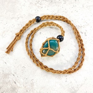 May include: A green agate stone pendant wrapped in brown macrame cord, hanging from a brown cord necklace with black beads.