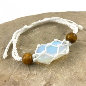 May include: White macrame bracelet with a white opal stone and two brown wooden beads.