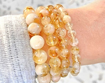 Puede incluir: Un conjunto de cuatro pulseras hechas con cuentas redondas de piedras preciosas transparentes, amarillas y blancas.