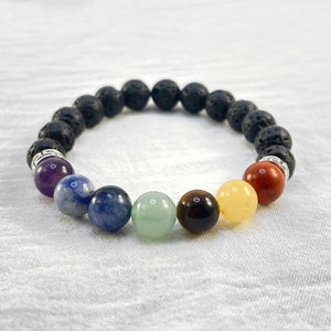 May include: A black lava rock bracelet with seven chakra beads. The beads are amethyst, blue lace agate, sodalite, aventurine, tiger's eye, citrine, and red jasper.