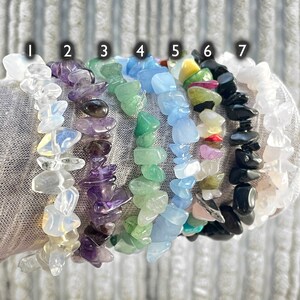 Puede incluir: Siete pulseras hechas de diferentes tipos de piedras. Las pulseras est&aacute;n apiladas una encima de la otra y est&aacute;n numeradas del 1 al 7. Las piedras son transparentes, moradas, verdes, azules, amarillas, rojas y negras.
