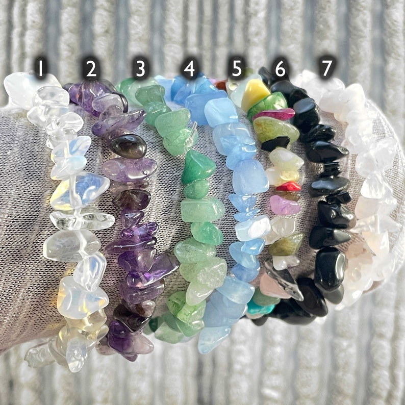 Puede incluir: Siete pulseras hechas de diferentes tipos de piedras. Las pulseras est&aacute;n apiladas una encima de la otra y est&aacute;n numeradas del 1 al 7. Las piedras son transparentes, moradas, verdes, azules, amarillas, rojas y negras.