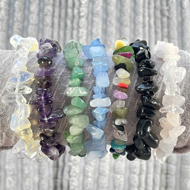 Puede incluir: Ocho pulseras hechas de varias piedras semipreciosas, incluyendo amatista, cuarzo transparente, cuarzo rosa, &oacute;nix negro y aventurina verde. Las pulseras est&aacute;n apiladas en la mu&ntilde;eca de una persona.