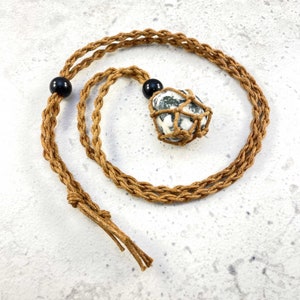May include: A brown braided cord necklace with a black bead and a white and green agate stone wrapped in brown cord.