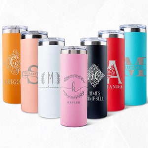 May include: A selection of personalised stainless steel tumblers in shades like orange, peach, white, pink, black, red, and teal. Each tumbler has a unique engraved design with names or initials. The tumblers have a silver lid.