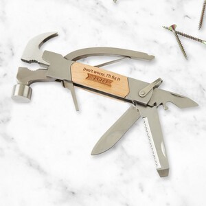 Peut inclure: Un outil multifonction avec un marteau, une pince, un couteau, une scie et un ouvre-bouteille. Le manche est en bois et porte la mention "Ne t'inquiète pas, je vais réparer ça" et "James" gravée.