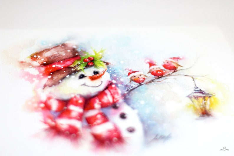 May include: Watercolour painting of a snowman wearing a red and white striped scarf and a brown hat with holly and red berries. Three red birds with Santa hats are perched on a branch in the background.