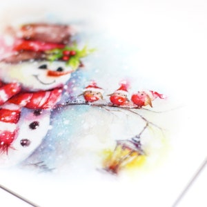 May include: Watercolour painting of a snowman wearing a red and white striped scarf and a red hat. Three red birds are perched on a branch with a yellow lantern in the background.