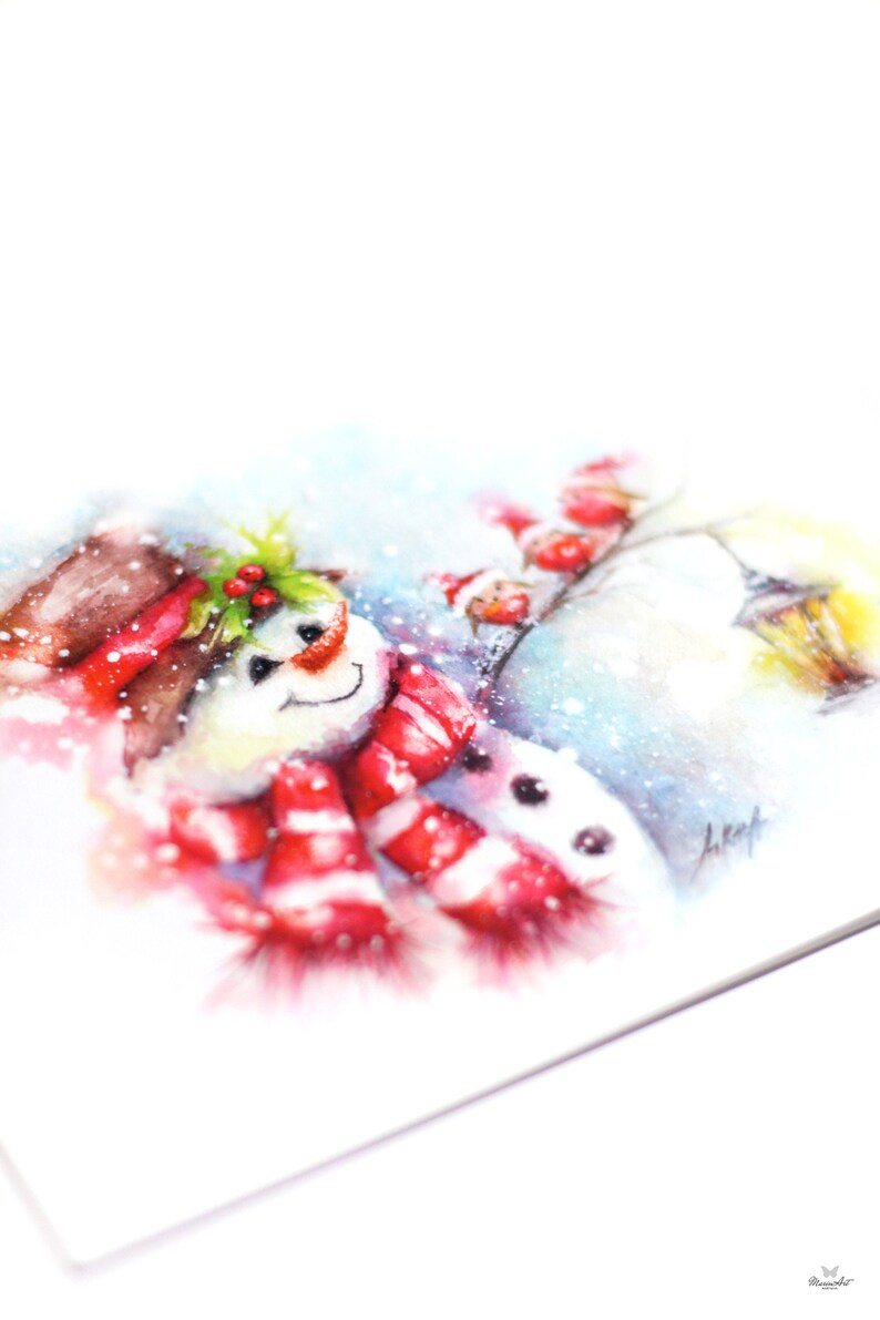 May include: A watercolour painting of a snowman wearing a red and white striped scarf and a brown hat with holly berries. The snowman is smiling and has a black button nose. The background is a snowy winter scene with a blue sky and a few snowflakes.