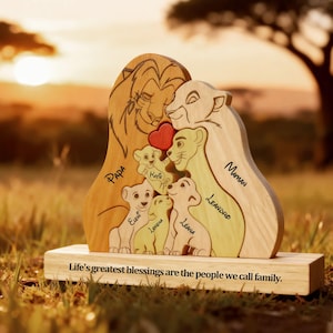 Può includere: Scultura in legno a forma di famiglia di leoni. Le parole "Papa", "Maman" e i nomi dei bambini sono incise. Un cuore rosso è tra i genitori. La base recita: "Life's greatest blessings are the people we call family."