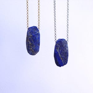 Può includere: Due collane con un ciondolo in pietra di lapislazzuli blu grezzo. Una collana ha una catena d'oro e l'altra una catena d'argento.