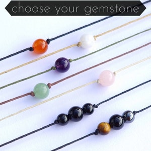 Puede incluir: Una variedad de pulseras de piedras preciosas sobre un fondo blanco. Las pulseras presentan diferentes piedras preciosas, incluyendo cornalina, amatista, aventurina, cuarzo rosa, howlite blanco, ónix negro y ojo de tigre.