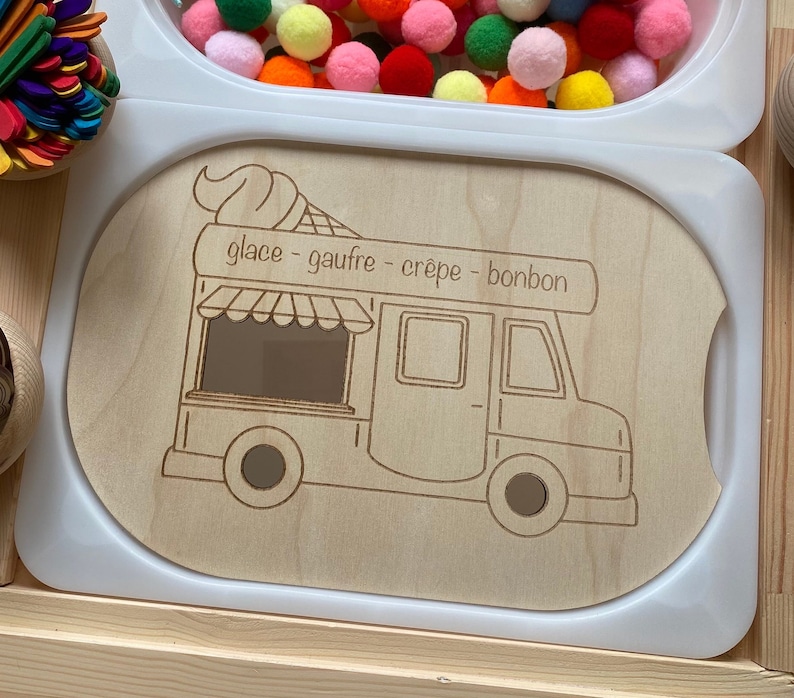 May include: A wooden play food truck with a white background. The truck has a window, a door, and wheels. The text "glace - gaufre - crepe - bonbon" is written on the truck.