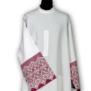 May include: White liturgical alb with a burgundy lace trim around the sleeves and bottom hem. The lace features a delicate floral design.