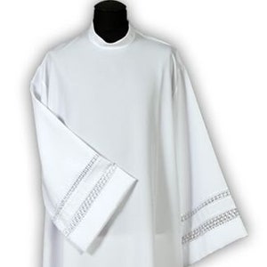 May include: White liturgical robe with a high neck and lace trim around the sleeves and hem.